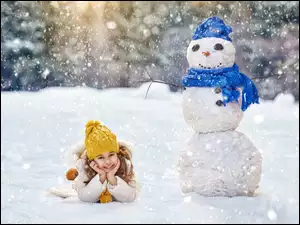 Dziewczynka odpoczywa na śniegu po lepieniu bałwana
