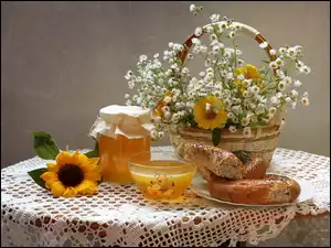 Kwiatki rumianku w koszyku i bułki z miodem na stole