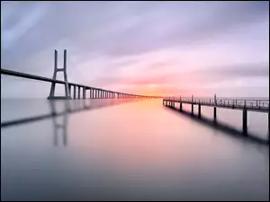 Most Vasco da Gamy i molo na rzece Tag w Portugalii w basku wschodzącego słońca