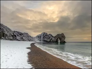 Ośnieżone skały przy zimowym brzegu morskiej plaży