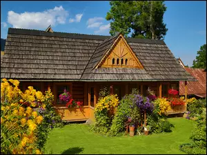Drewniany dom w ogrodzie pełnym kwiatów
