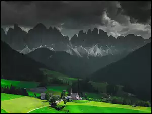 Domy i kościół w dolinie z widokiem na wysokie Alpy