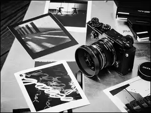 Czarno białe zdjęcie aparatu fotograficznego marki Olympus obok rozrzuconych zdjęć