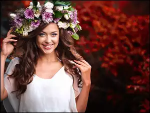 Uśmiechnięta brunetka w kwiatowym wianku na głowie
