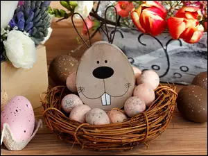 Wielkanocna dekoracja z zabawnym zajączkiem w koszyku obok jaj