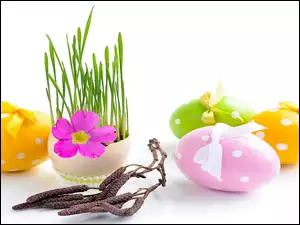 Wielkanocne pisanki obok zielonej trawki i uschniętej gałązki leszczyny