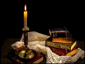 Kompozycja z książkami leżącymi na serwecie i świecą w świeczniku