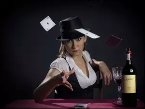 Kobieta rzucająca karty na stół obok kieliszka i butelki wina