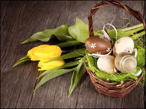 Wielkanocna kompozycja z bukietem żółtych tulipanów przy koszyczku z pisankami