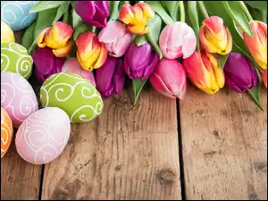 Wielkanocna kompozycja kolorowych tulipanów i pisanek na deskach