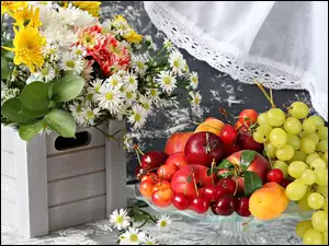 Bukiet kwiatów w skrzynce obok owoców na kloszu