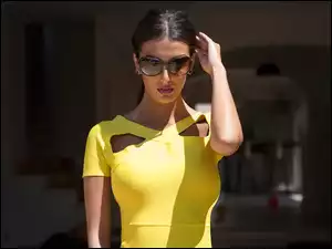 Brunetka w okularach przeciwsłonecznych i letniej żółtej sukience