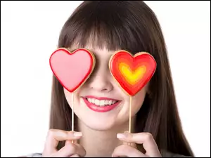Walentynkowe lizaki w kształcie serc na oczach uśmiechniętej kobiety