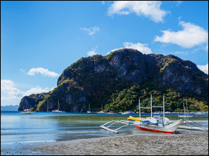 Katamaran na filipińskim brzegu morza z widokiem na łódki i skały
