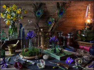 Bukiety kwiatów lampa moździerze i inne przedmioty rozrzucone na stole na stole