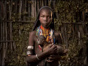 Etiopska dziewczyna trzyma małą kózkę na rękach