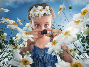 Dziewczynka z małym aparatem fotograficznym robi zdjęcia kwiatom