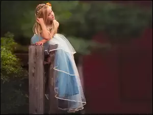 Dziewczynka w niebieskiej tiulowej sukience z wiankiem na głowie