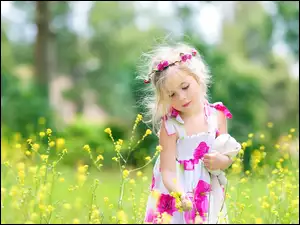 Dziewczynka z wiankiem wśród kwiatów na łące