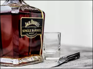 Butelka whisky obok szklanki i noża