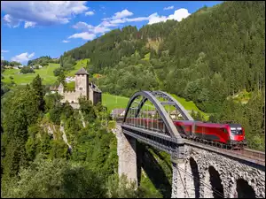 w Tyrolu na moście nadjeżdzający pociąg z zamkiem w tle