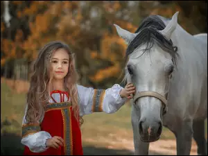 Dziewczynka z długimi włosami obok konia