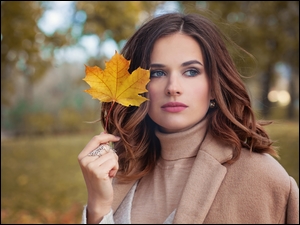 Modelka z jesiennym liściem w parku