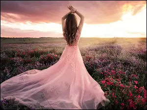 Kobieta w różowej sukni na polu kwiatowym