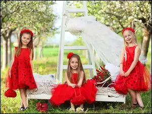 Dziewczynki w czerwonych sukienkach w sadzie