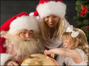 Mikołaj ze Śnieżynką i dziewczynka pokazująca palcem po globusie