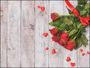 Bukiet róż z czerwoną wstążeczką i serduszkami na deskach