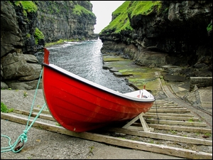 Czerwona łódka nad rzeką płynąca między skałami