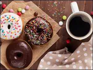 Pączki donuty z kubkiem kawy i cukierkami na deskach