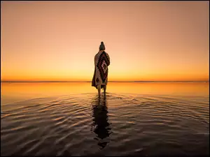 Kobieta nad zatoką o zachodzie słońca