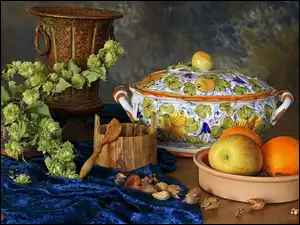 Kompozycja z wazą jabłkiem i pomarańczami w miseczce i chmielem