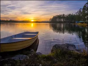 Wschód słońca nad jeziorem z drzewami i łódką