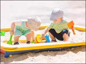 Dwóch chłopców z zabawkami w piaskownicy