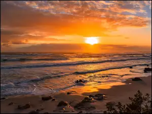 Zachód słońca nad brzegiem morza z falami