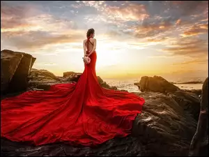 Kobieta w czerwonej sukni nad morzem