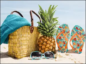 Koszyk z okularami japonkami i ananasem na plaży