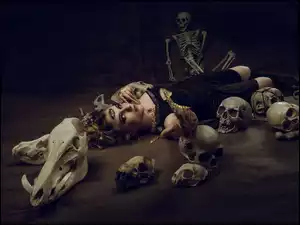 Kobieta wśród szkieletu i czaszek