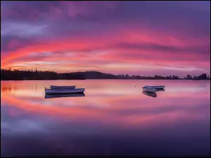Zachód słońca nad jeziorem z łódkami