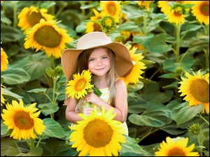 Uśmiechnięta dziewczynka z kapeluszem i słonecznikami
