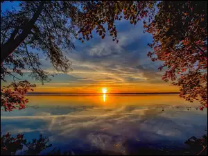 Zachód słońca nad jeziorem i drzewem
