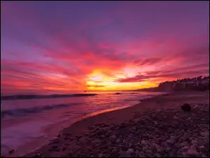 Zachód słońca nad kamienistą morską plażą
