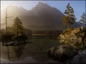 Mgliste górskie jezioro z świerkami