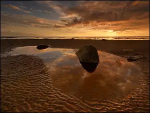 Kamienie na brzegu morza w zachodzącym słońcu