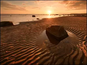 Zachód słońca nad morską kamienistą plażą