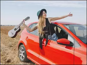 dziewczyna z gitarą w czerwonym samochodzie