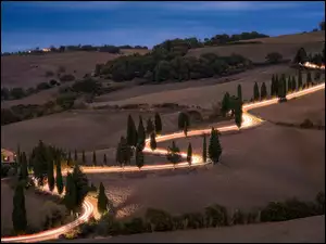 Oświetlona droga prowadząca przez toskańskie pola
